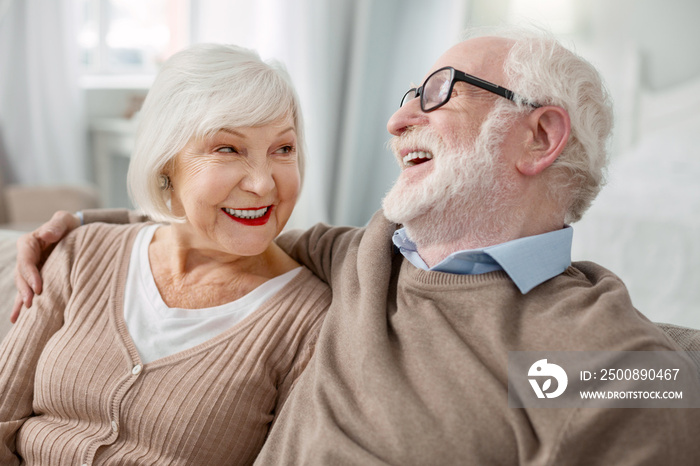 Elderly couple. Cheerful elderly man sitting together with his wife while hugging her