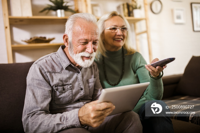 Senior couple sitting in sofa and watching tv