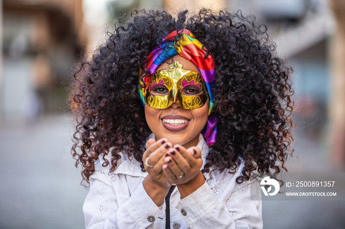 Carnaval party. Brazilian curly hair woman in costume blowing confetti