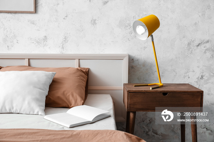 Yellow lamp on wooden bedside table in light room