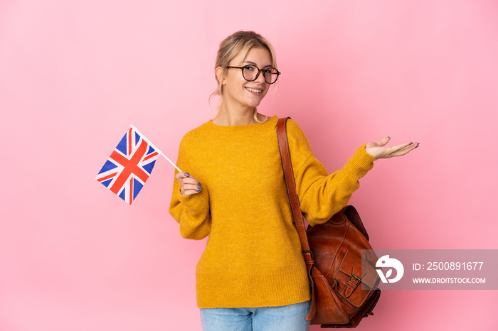 Young Russian woman holding an United Kingdom flag isolated on pink background extending hands to the side for inviting to come