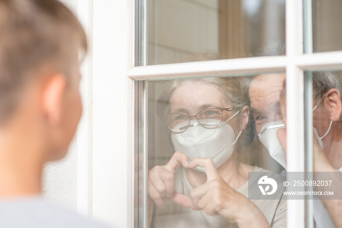 Boy communicates with his grandparents through a window during the coronavirus epidemic