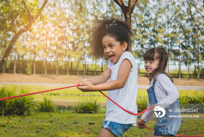 Happy kids playing rope tug of war in park