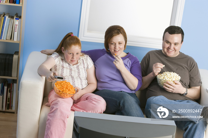 Happy obese family watching television together