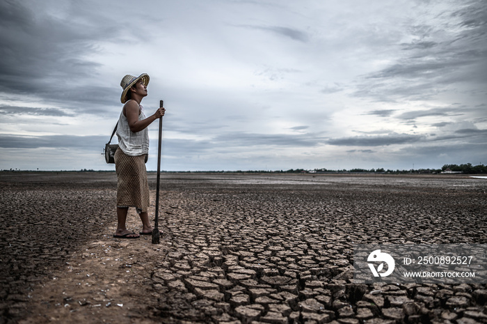 Women standing on dry soil and fishing gear, global warming and water crisis