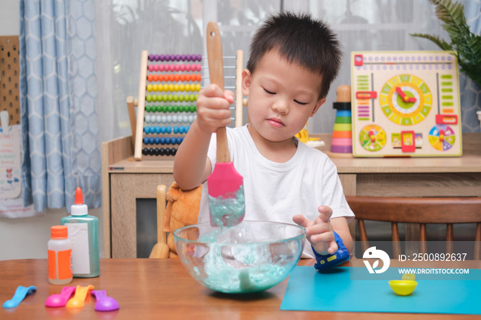 Cute  Asian 4 years old boy having fun making fluffy slime, Young kid having fun playing and being creative by science experiment homemade toy called Slime