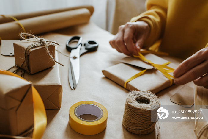 Woman packaging box. Kraft wrapping paper and natural twine. Recycling material. Happy holiday present, surprise. Gifts for boxing day. Delivery service, shipping. Handwork art craft. Celebration