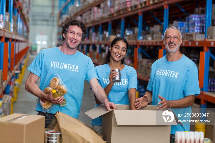 Three volunteers packing eatables in cardboard box