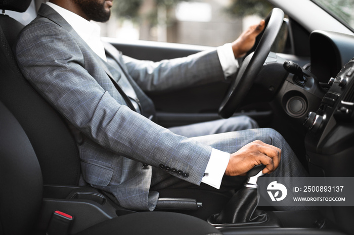 Closeup of black man in suit changing gears in car