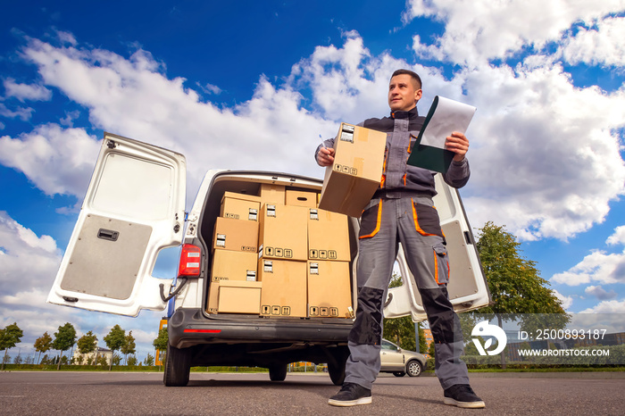 shopping delivery concept. Courier is engaged in shopping delivery. Courier near van with boxes. Express van with many boxes. Portrait of delivery man on street. He holds clipboard and box