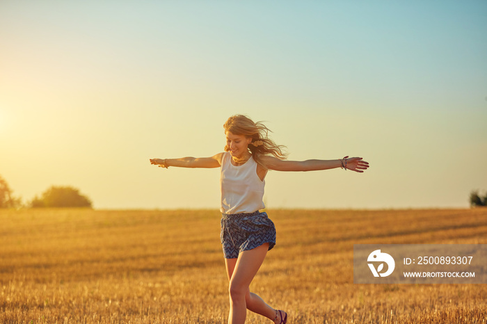 Cute young woman jumping in a wheat field.