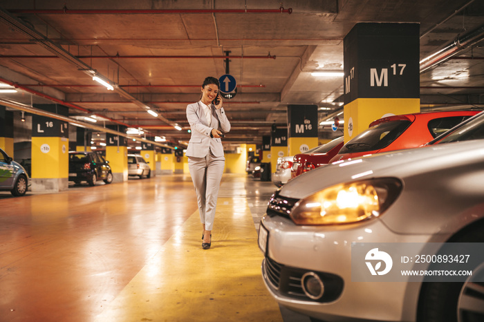 Elegant businesswoman locking her car with keys in underground parking.