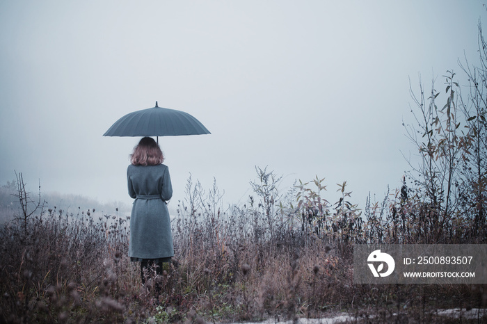 young girl with umbrella in autumn field