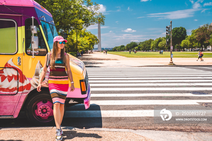 Young girl buying ice cream in an ice cream truck near Washington monument on sunny day with blue sky background.