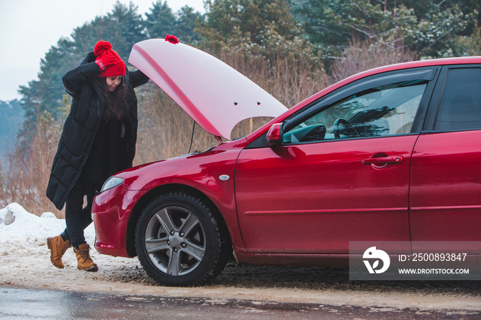 woman looking at engine broken car at winter road side