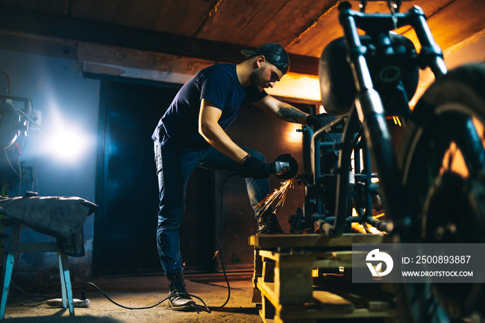 Motorcycle repair. Young man repairing motorbike in garage. Mechanic fixing motorcycle engine.