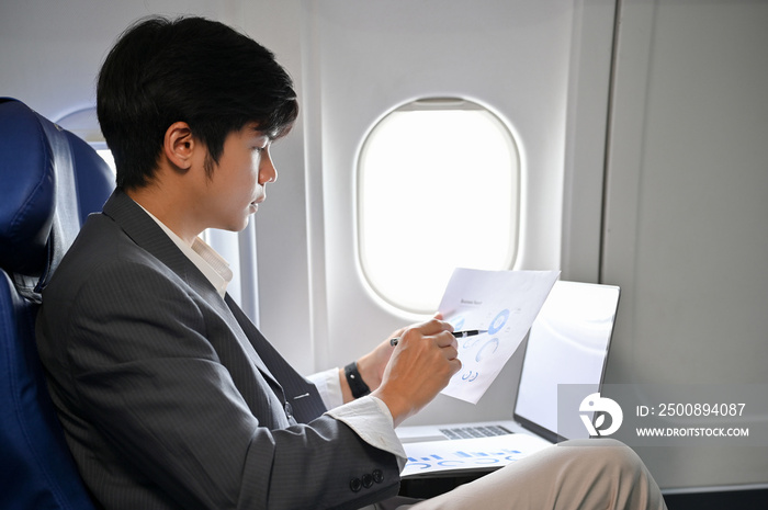 Professional Asian businessman concentrating analyzing a financial data during the flight