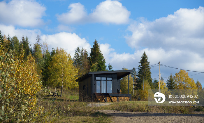 Black wooden cabin in colorful forest in autumn