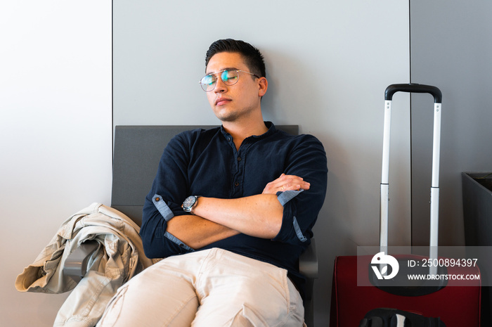 Front view handsome young man sleeping on a chair in a waiting lounge in airport.