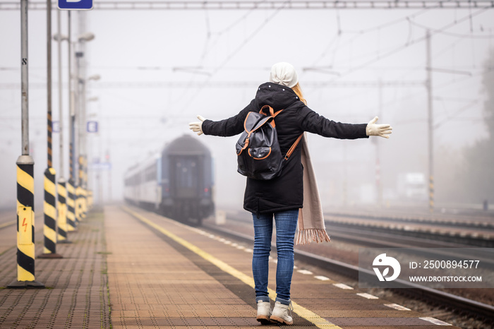 Disappointed traveler missed train. Woman tourist is looking at leaving train on railroad station