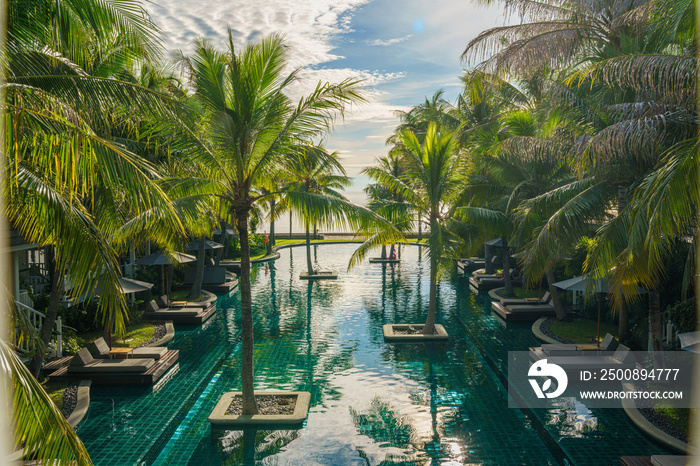 swimming pool surround with coconut tree and bangalows at seaside resort