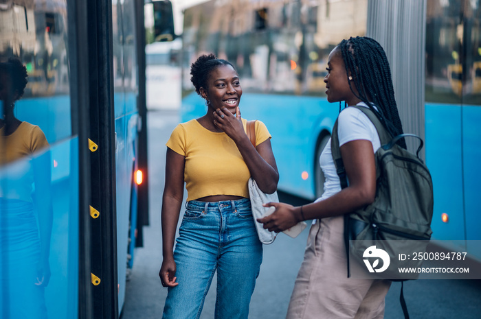 Two african american woman waiting for a public transport at a bus stop