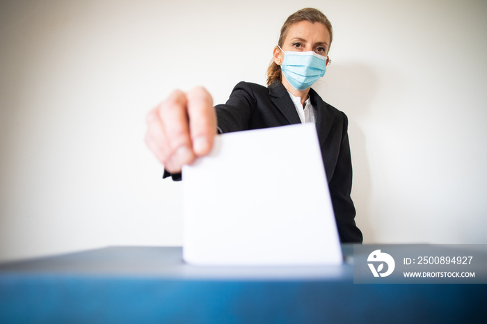 woman wearing mask putting vote in ballot