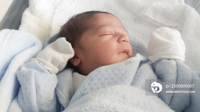 two days old newborn baby boy in hospital cot