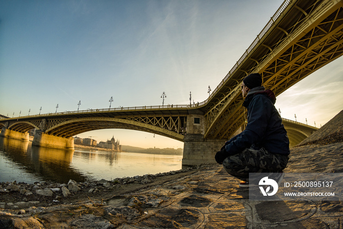 Man alone under Margaret bridge of Budapest at sunset