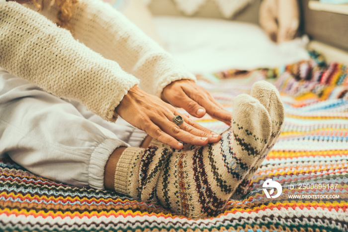 Close up of woman doing stretching exercises on the bed wearing colorful winter warm wool socks. Concept of healthy lifestyle people. Exercises for aged mature female. Touching feet with hands