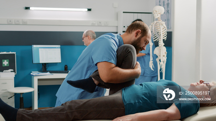 Physiotherapist assisting elder patient with physical injury, giving support at medical procedure appointment. Osteopath and senior woman doing muscles rehabilitation exercise for recovery.