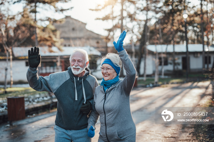 An older married couple enjoys exercising and jogging on a beautiful sunny winter day.