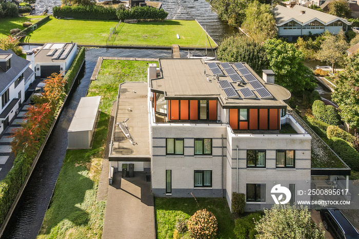 an aerial view of a house with solar panels on the roof, and green grass in the yard is surrounded by trees