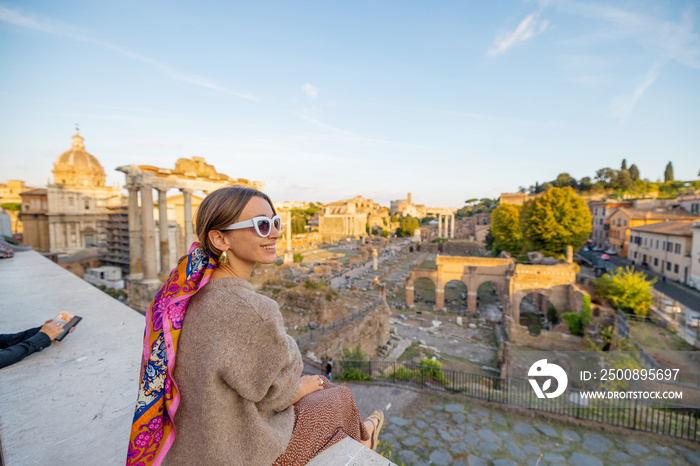 Woman enjoying view on the Roman Forum, ruins at the center of Rome on a sunset. Concept of traveling famous landmarks in Italy. Caucasian woman wearing colorful shawl in hair and sunglasses