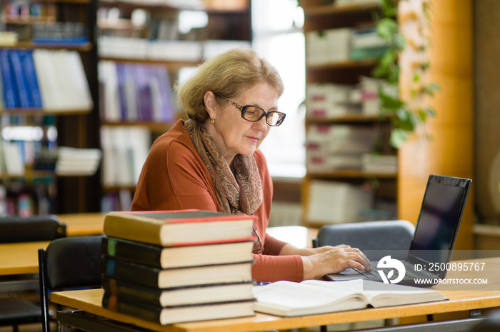 Senior woman using laptop in library