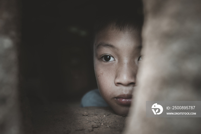 Closeup poor boy peeking out of a dilapidated house, Concept of assistance to the poor, human rights.