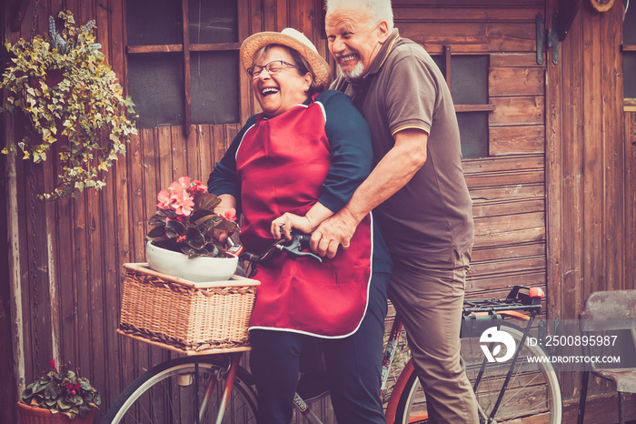 One old senior couple have fun together playing and joking outdoor on a bike. Active mature man and woman aging youthfully with love and happiness. Active lifestyle for elderly people enjoying life