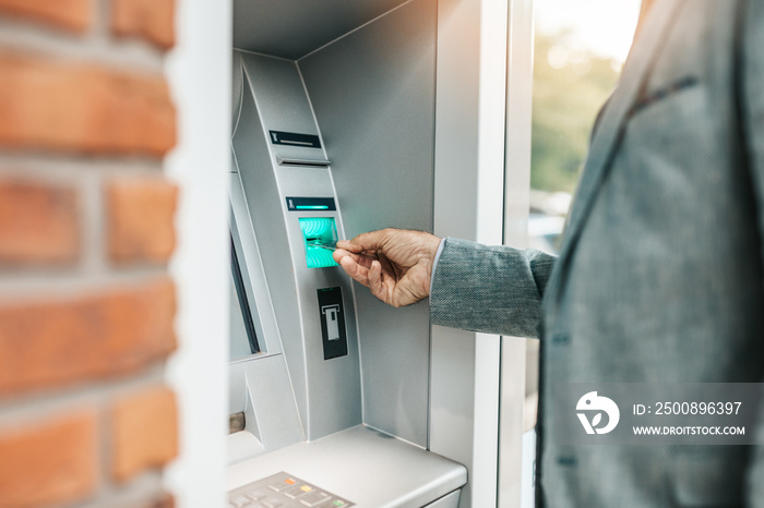 A senior man withdraws money from an automated teller machine (ATM).