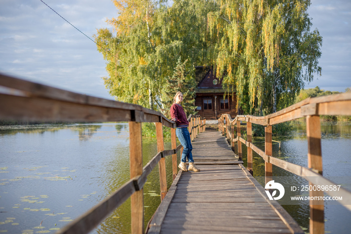 Tourist woman walk by long wooden suspension bridge above river