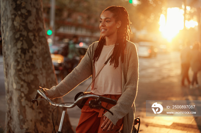 African American woman with bicycle in city.