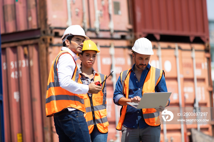 Hispanic man harbor worker talking on the walkie-talkie radio and control loading containers at container warehouse. container yard port of import and export goods