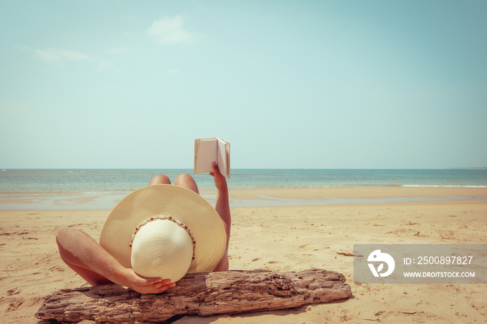 Leisure in summer - Young woman in straw hat lying sunbathe on a tropical beach, relax with book. Memories of summer vacation concept. retro color tone.