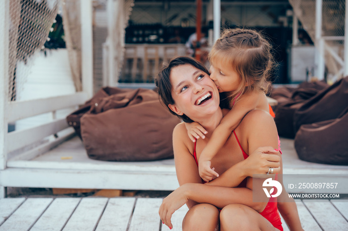 Young mother giving daughter piggyback ride on the beach