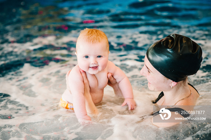 whirlpool, jacuzzi. Diving baby in the paddling pool. Young mother, swimming instructor and happy little girl in pool. Learn infant child to swim. Enjoy the first day of swimming in water.