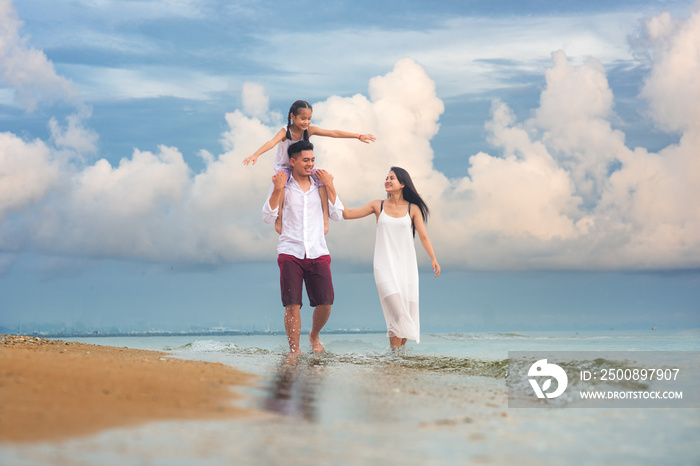 Happy asian family - father, mother, kid hold hands and run piggyback together with fun along daylight sea beach. Travel, active lifestyle, parents with children on tropical summer vacations.