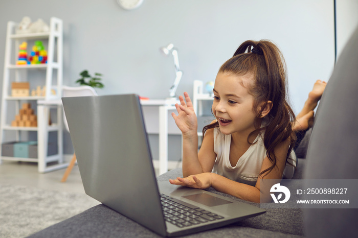 Little girl talking to family, friend or school teacher online from home. Lovely kid using laptop for communication