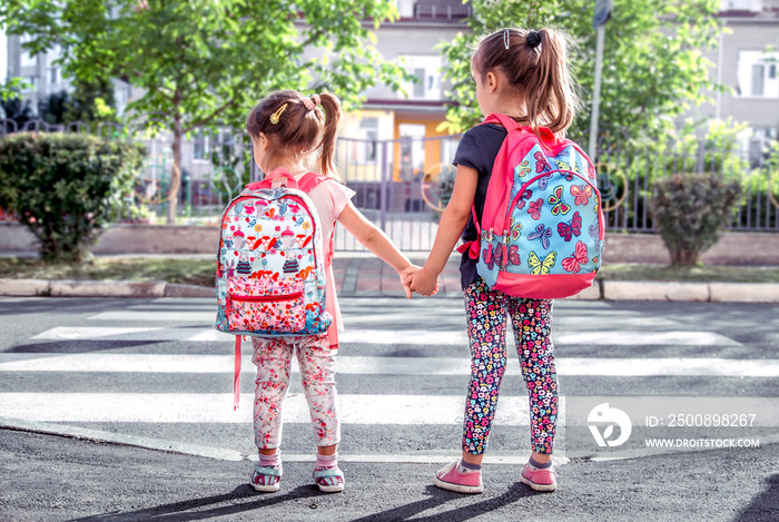 Children go to school, happy students with school backpacks and holding hands together