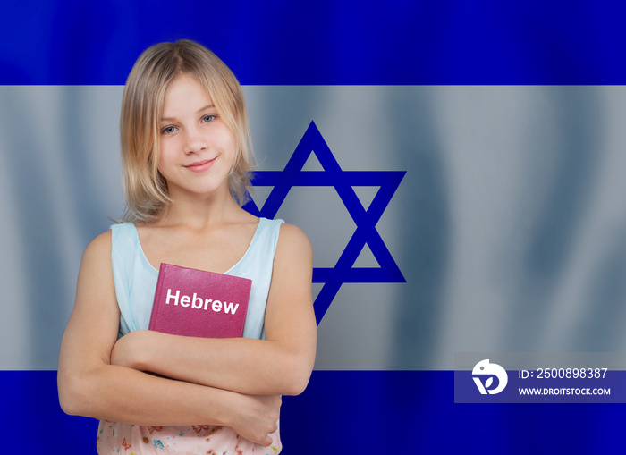 Cute blonde teen girl embracing book with inscription Hebrew in Hebrew language on flag of Israel background