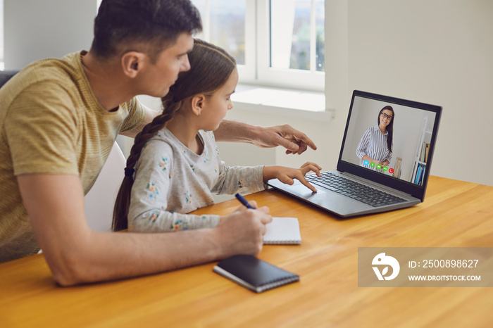 Online learning lessons education school. Father and daughter are doing online education with a teacher using a laptop sitting at home.