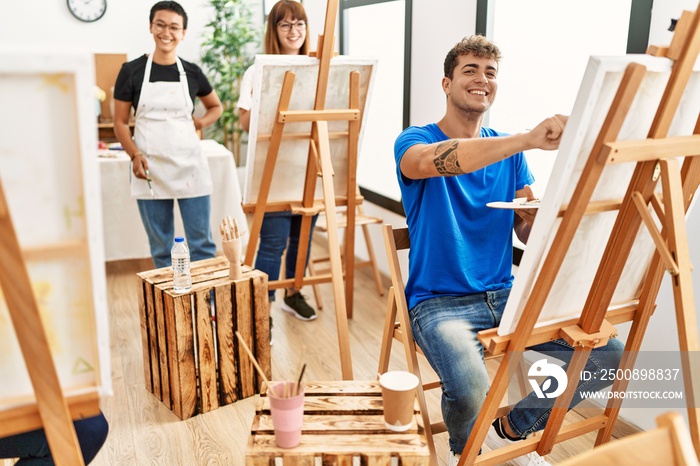 Young man smiling happy drawing with group of people at art studio.